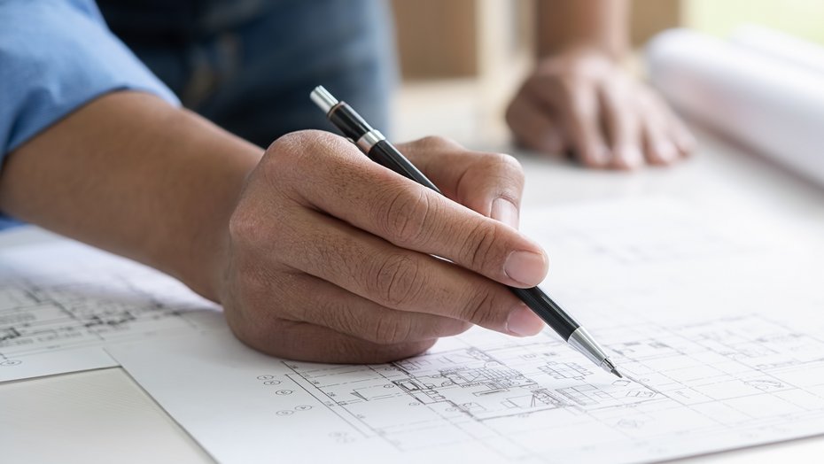 Ingenieur, der an Bauplan arbeitet Ingenieur, der im Büro an Bauplan arbeitet