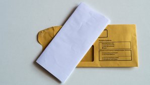 Kuvert mit Briefbogen Ein gefalteter Briefbogen liegt auf einem Kuvert, auf dem Persönliche Zustellung steht.