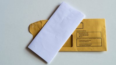 Kuvert mit Briefbogen Ein gefalteter Briefbogen liegt auf einem Kuvert, auf dem Persönliche Zustellung steht.