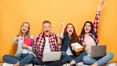 Ausbildung und Praktika Gruppe von 4 jungen Menschen, die vor einer orangefarbenen Wand sitzen