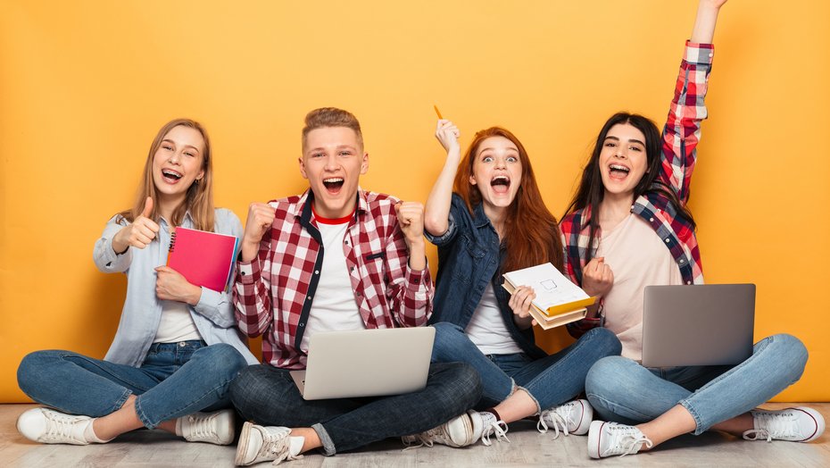 Gruppe von 4 jungen Menschen, die vor einer orangefarbenen Wand sitzen