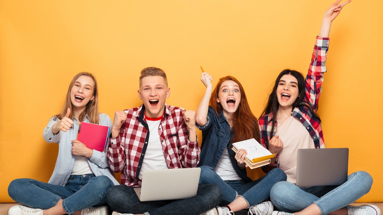 Gruppe von 4 jungen Menschen, die vor einer orangefarbenen Wand sitzen