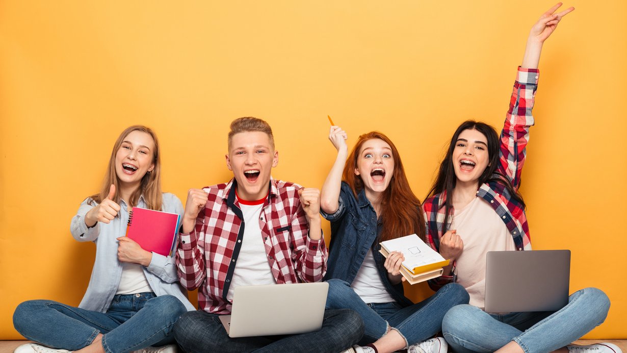 Gruppe von 4 jungen Menschen, die vor einer orangefarbenen Wand sitzen
