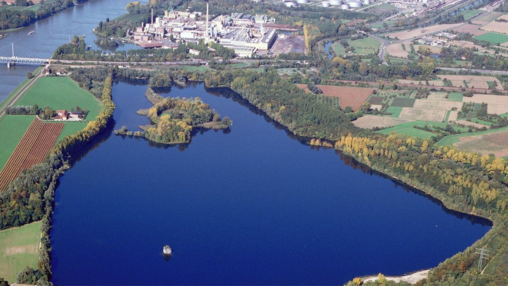 Luftaufnahme vom Knielinger See und Federbach am Rhein mit angrenzenden Äckern, Wiesen und Wäldern sowie Industrieanlagen und Versorgungseinrichtungen
