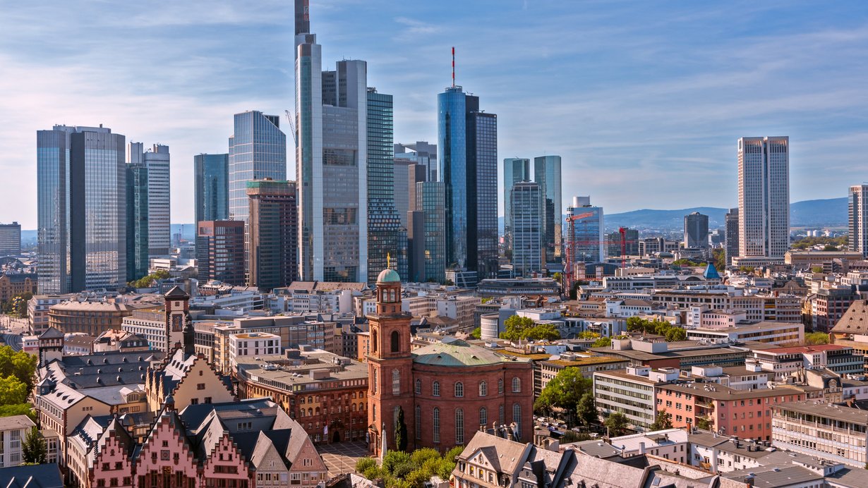 Frankfurt am Main in der Gegenwart. Vorne links der spätmittelalterliche Römer, der nach den Zerstörungen des 2. Weltkriegs wieder aufgebaut wurde. Rechts daneben die Paulskirche, in der 1848/49 das erste gesamtdeutsche Parlament tagte und wo erstmals der Versuch gemacht wurde, einem geeinten Deutschland eine demokratische Verfassung zu geben. Im Hintergrund die moderne Frankfurter Skyline, die für die globalisierte und partiell „postindustrielle“ Welt des 21. Jahrhunderts steht.
