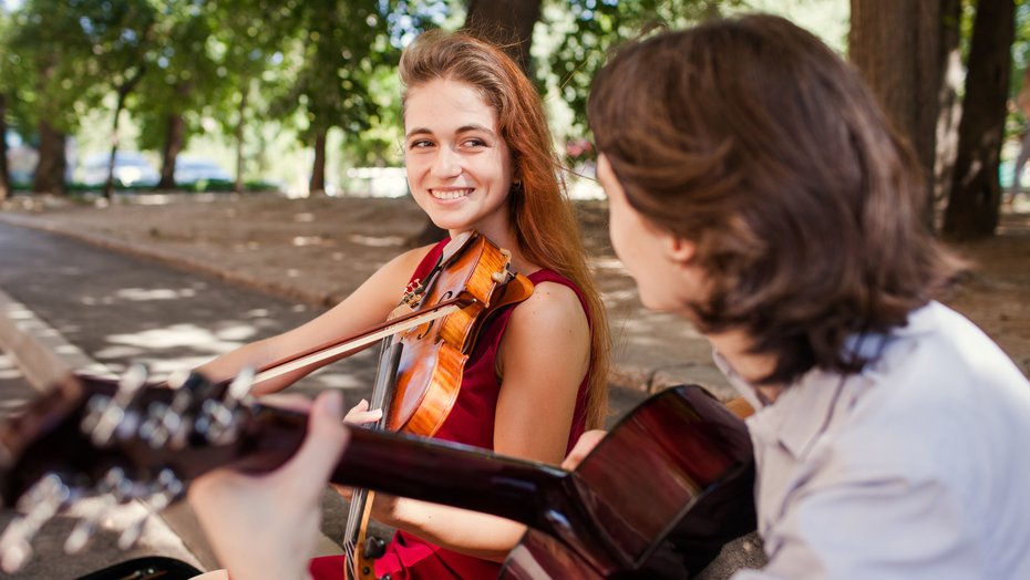 Straßenmusikerin und Straßenmusiker beim Geigen- bzw. Gitarrenspiel