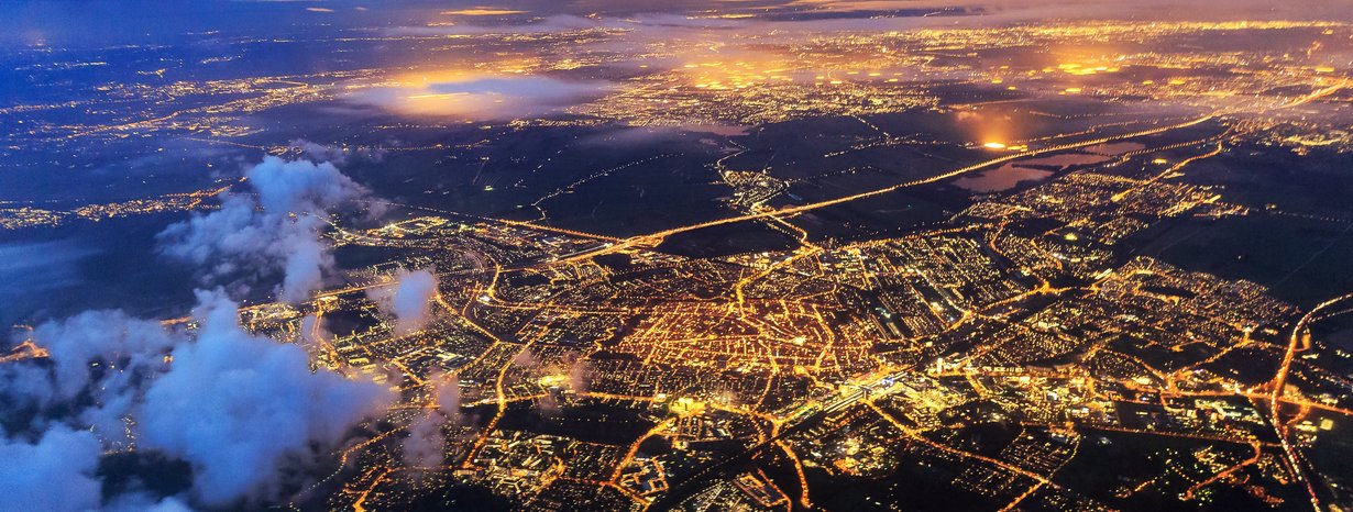 Luftaufnahme einer großen, hell erleuchteten Stadt.