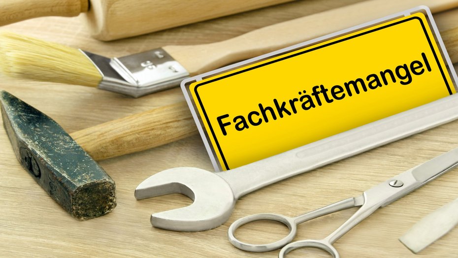 Fachkräftemangel Gelbes Schild "Fachkräftemangel" in Deutschland mit Werkzeugen auf Holz