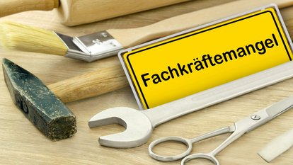 Fachkräftemangel Gelbes Schild "Fachkräftemangel" in Deutschland mit Werkzeugen auf Holz