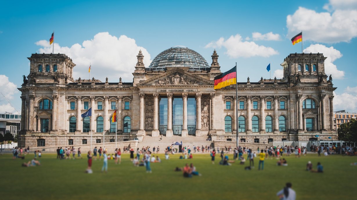 Viele Menschen an einem sonnnigen Tag auf der Wiese vor dem Reichstagsgebäude in Berlin