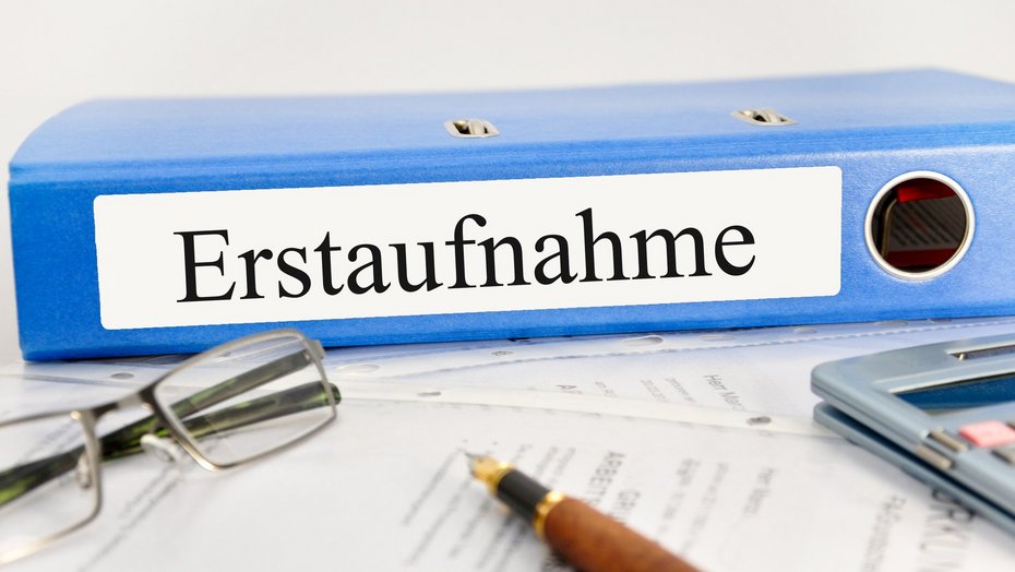 Ordner mit Beschriftung "Erstaufnahme" Ordner mit Beschriftung "Erstaufnahme", davor eine Brille, ein Füller und ein Taschenrechner