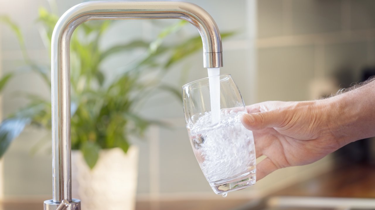 Bild zeigt ein Glas unter einem Wasserhahn