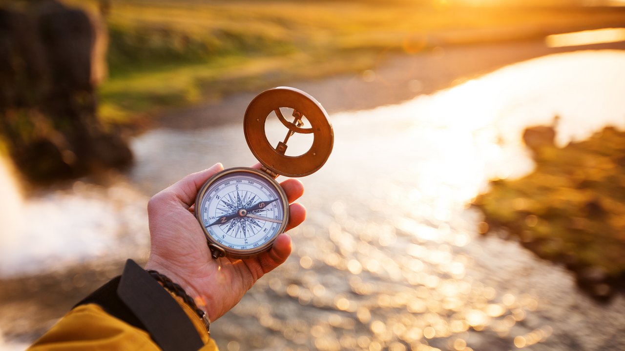 Landschaft mit altem Kompass auf der Hand des Reisenden. 