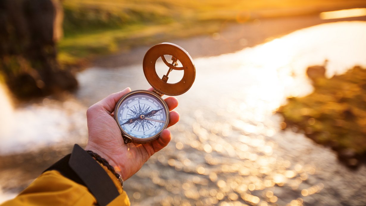 Landschaft mit altem Kompass auf der Hand des Reisenden. 