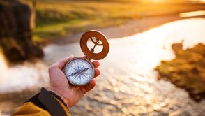 Landschaft mit altem Kompass auf der Hand des Reisenden. 