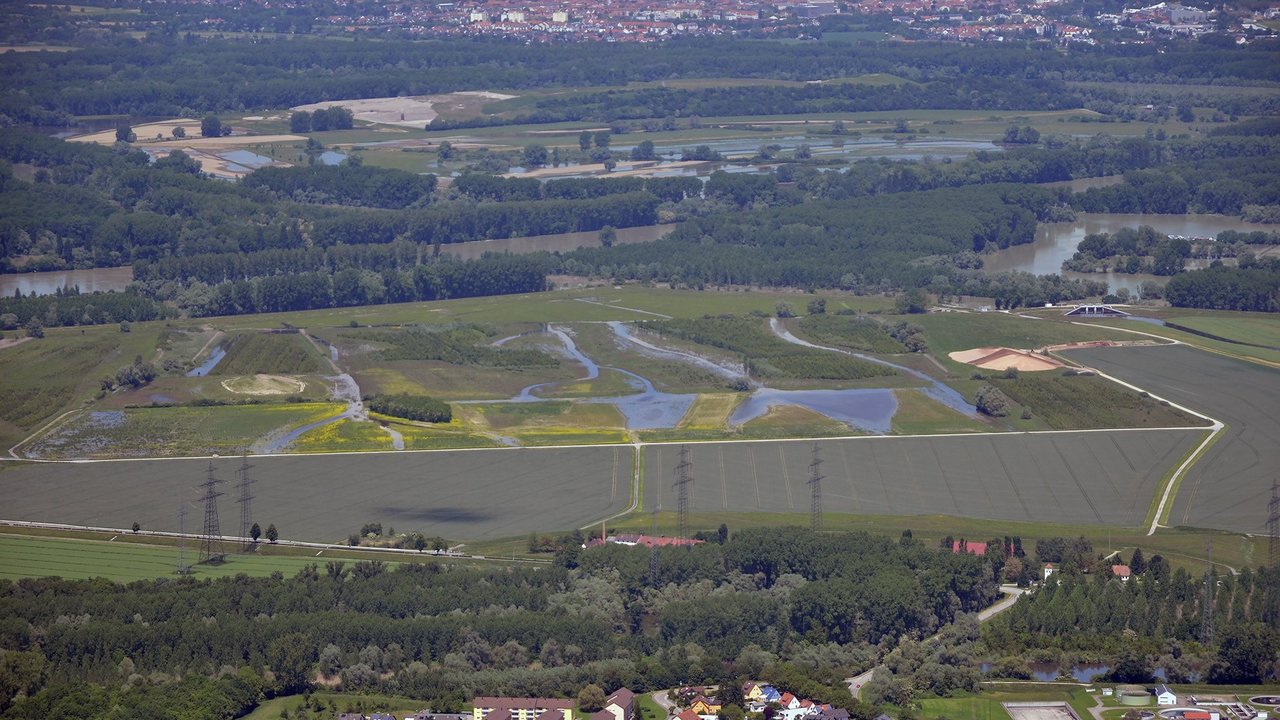 Luftbildaufnahme des Polder Rheinschanzinsel mit Blick in Richtung Norden. Zu sehen sind die mit Wasser gefüllten Gräben und Schluten im Bereich der Fläche für die partiellen Flutungen zur Auenrenaturierung. Im Hintergrund ist das überflutete Rheinvorland und auf der gegenüberliegenden Seite des Rheins der Polder Mechtersheim zu sehen.