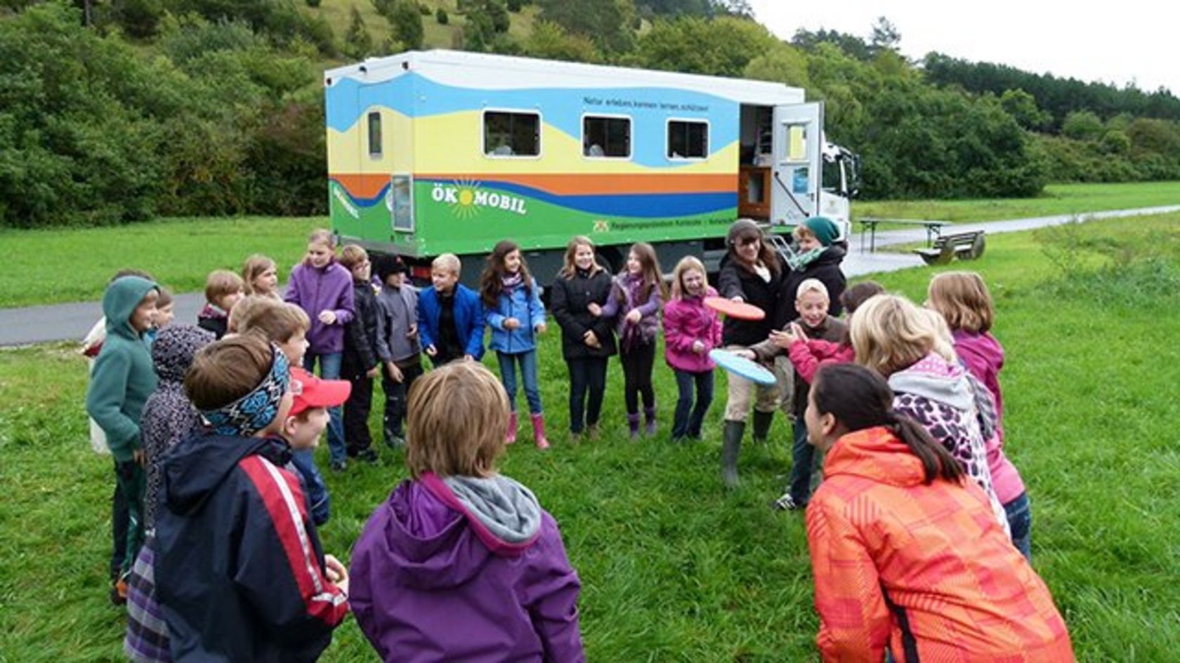 Kinder vor dem Ökomobil auf einer Wiese