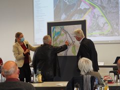 Mehrere Personen diskutieren an einem Plan Trassenvarianten. 