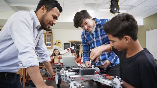 Lehrer mit Schülern, die ein Roboter-Fahrzeug im naturwissenschaftlichem Unterricht bauen