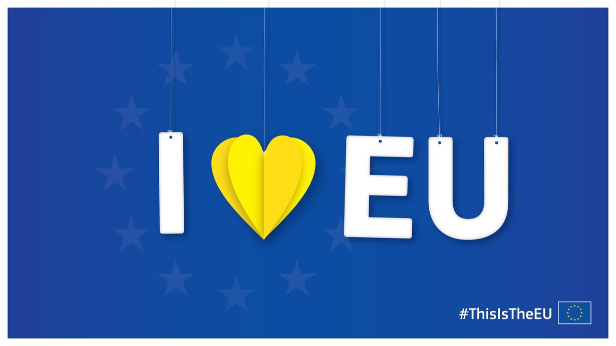 Auf blauem Hintergrund seht in weißen Buchstaben „I love EU“ wobei das love ein gelbes, aus Papier gefaltetes Herz ist. 