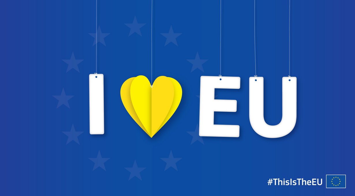 Auf blauem Hintergrund seht in weißen Buchstaben „I love EU“ wobei das love ein gelbes, aus Papier gefaltetes Herz ist. 