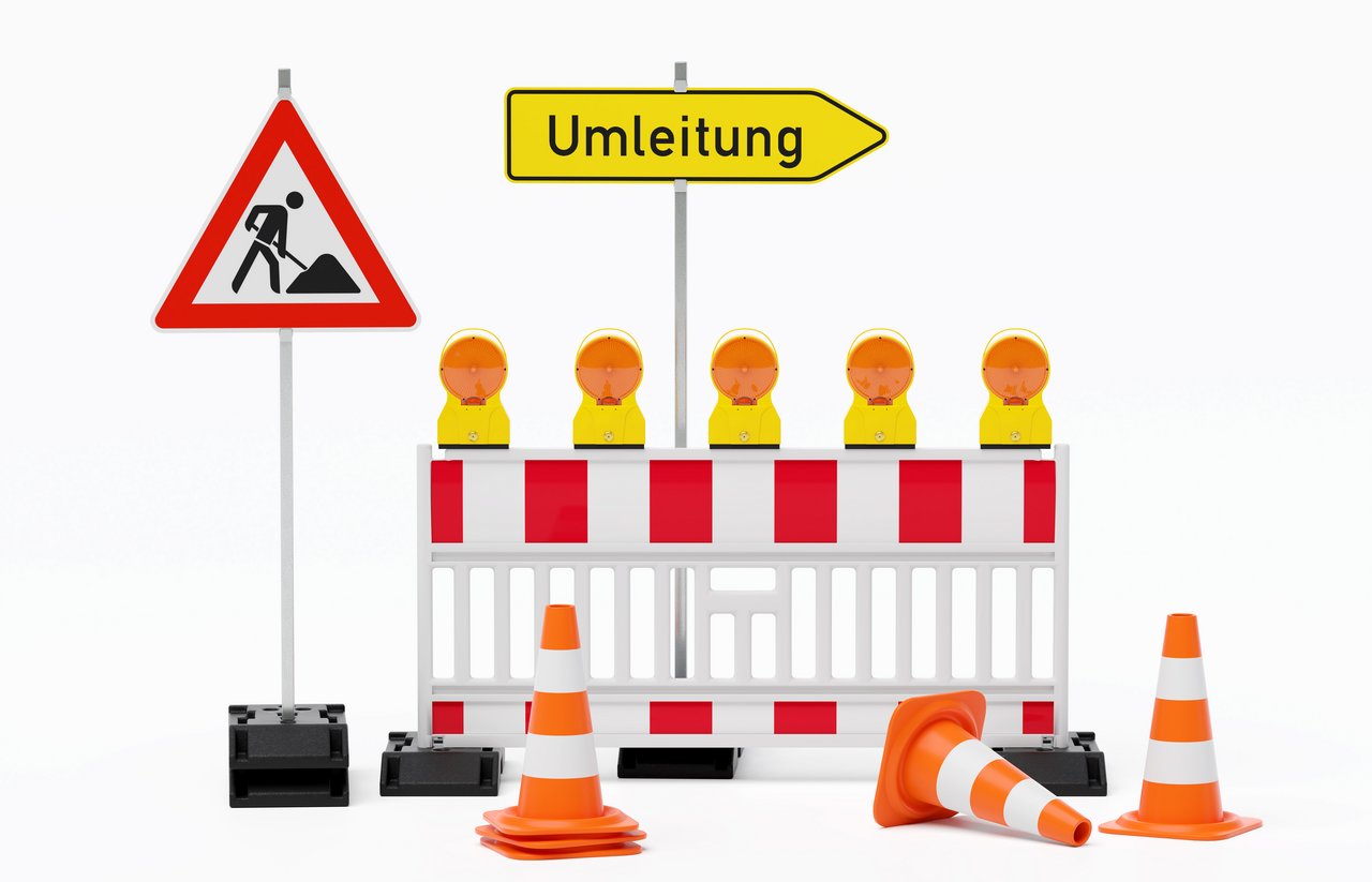 Einzelne Absturzsicherung mit 5 Bakenleuchten gelb-orange, Fußplatten, Schild Baustelle, Schild Umleitung rechtsweisend auf Pfosten steht daneben und Verkehrshütchen Pylone - freigestellt 
