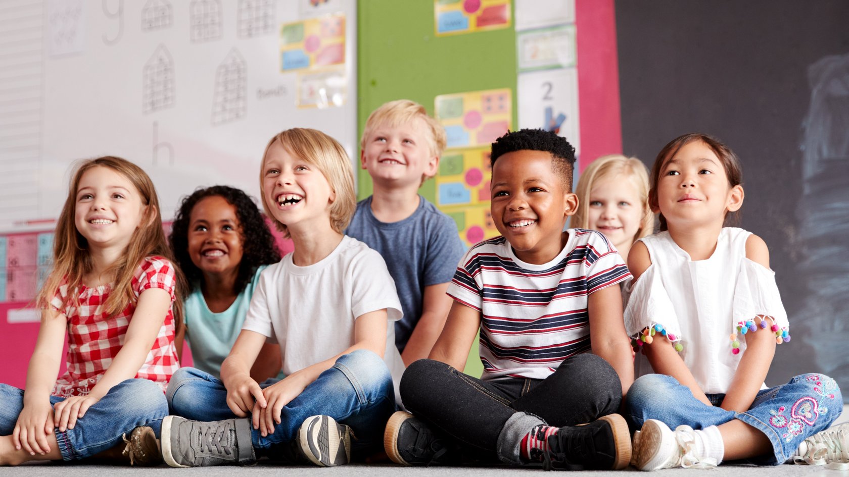 Gruppe von Grundschülern, die auf derm Boden im Klassenzimmer sitzen