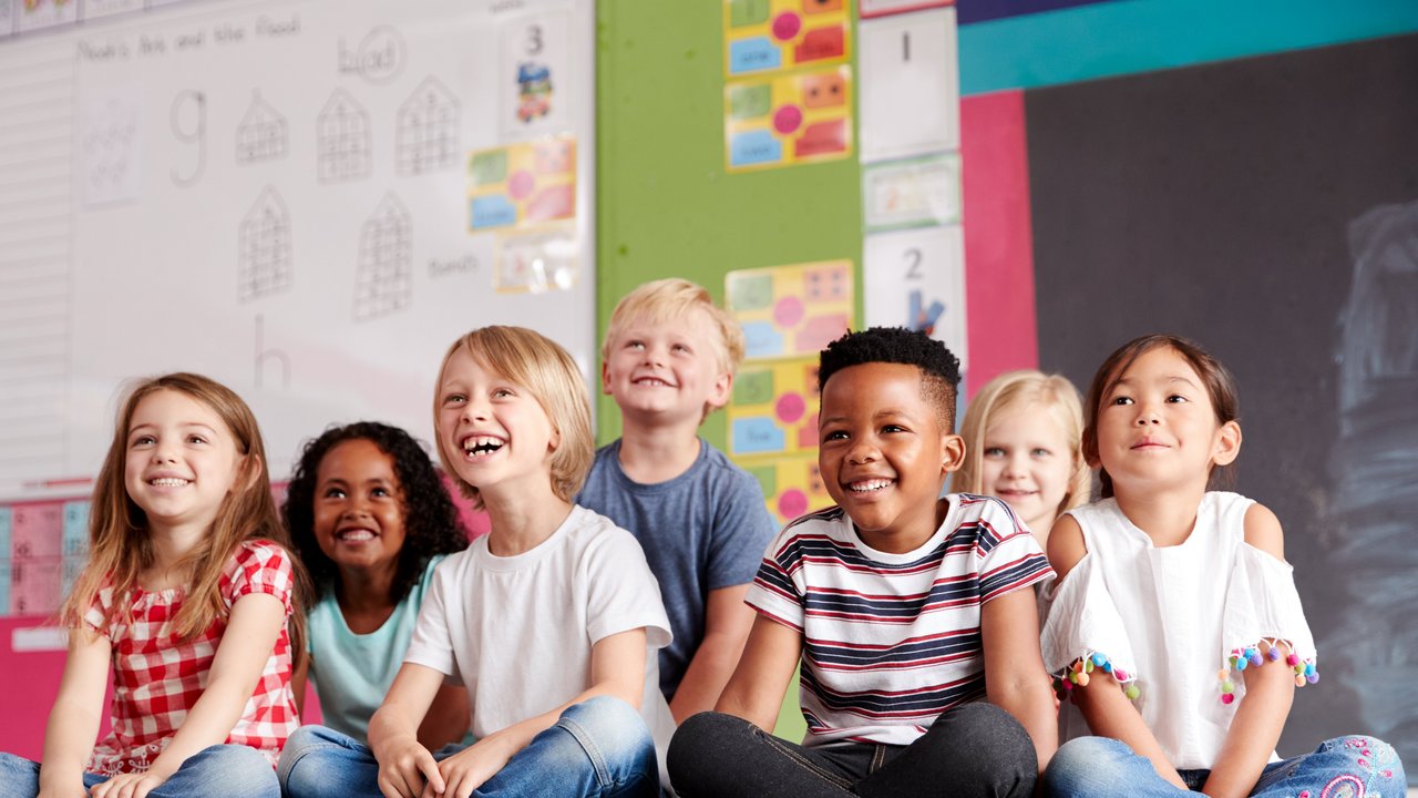 Grundschüler Gruppe von Grundschülern, die auf derm Boden im Klassenzimmer sitzen