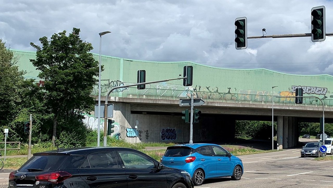 Fahrzeuge an Straßenkreuzung mit Ampeln und Straßenverkehrsschildern mit Blick auf den Einmündungsbereich L 607 und Mörscher-Straße, im Hintergrund Überführung der A 5