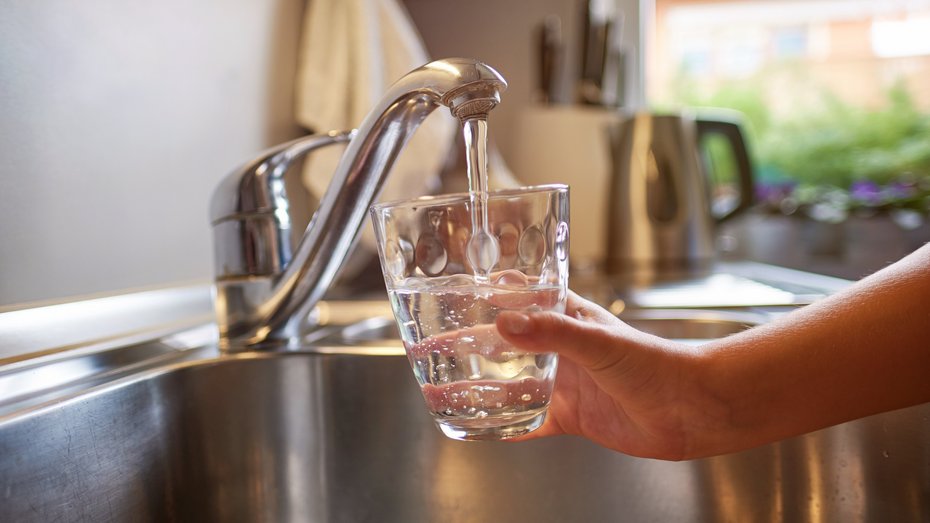 Trinkwasser Kinderhand, die sich am Wasserhahn frisches Wasser in ein Glas gießt