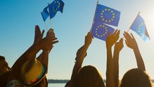 Hände schwenken Flaggen der EU Erhobene Hände, die kleine Flaggen der europäischen Union schwenken