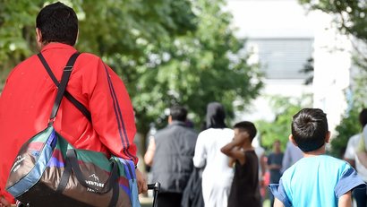 Flüchtlinge gehen am 04.08.2014 in der Landeserstaufnahme für Asylbewerber (LEA) in Karlsruhe (Baden-Württemberg) einen Weg entlang.