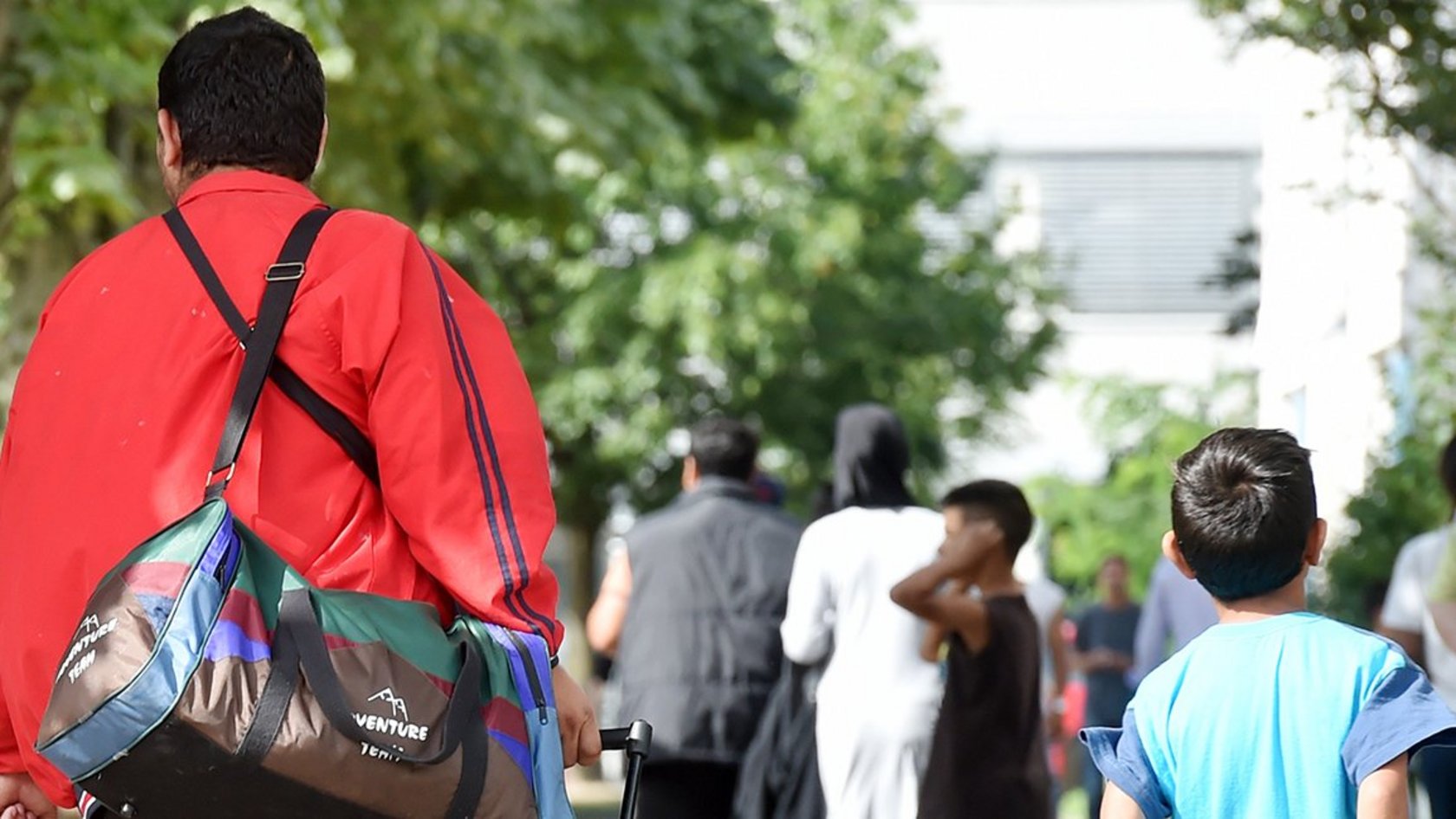 Flüchtlinge gehen am 04.08.2014 in der Landeserstaufnahme für Asylbewerber (LEA) in Karlsruhe (Baden-Württemberg) einen Weg entlang.