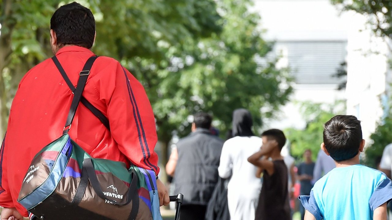 Flüchtlinge gehen am 04.08.2014 in der Landeserstaufnahme für Asylbewerber (LEA) in Karlsruhe (Baden-Württemberg) einen Weg entlang.