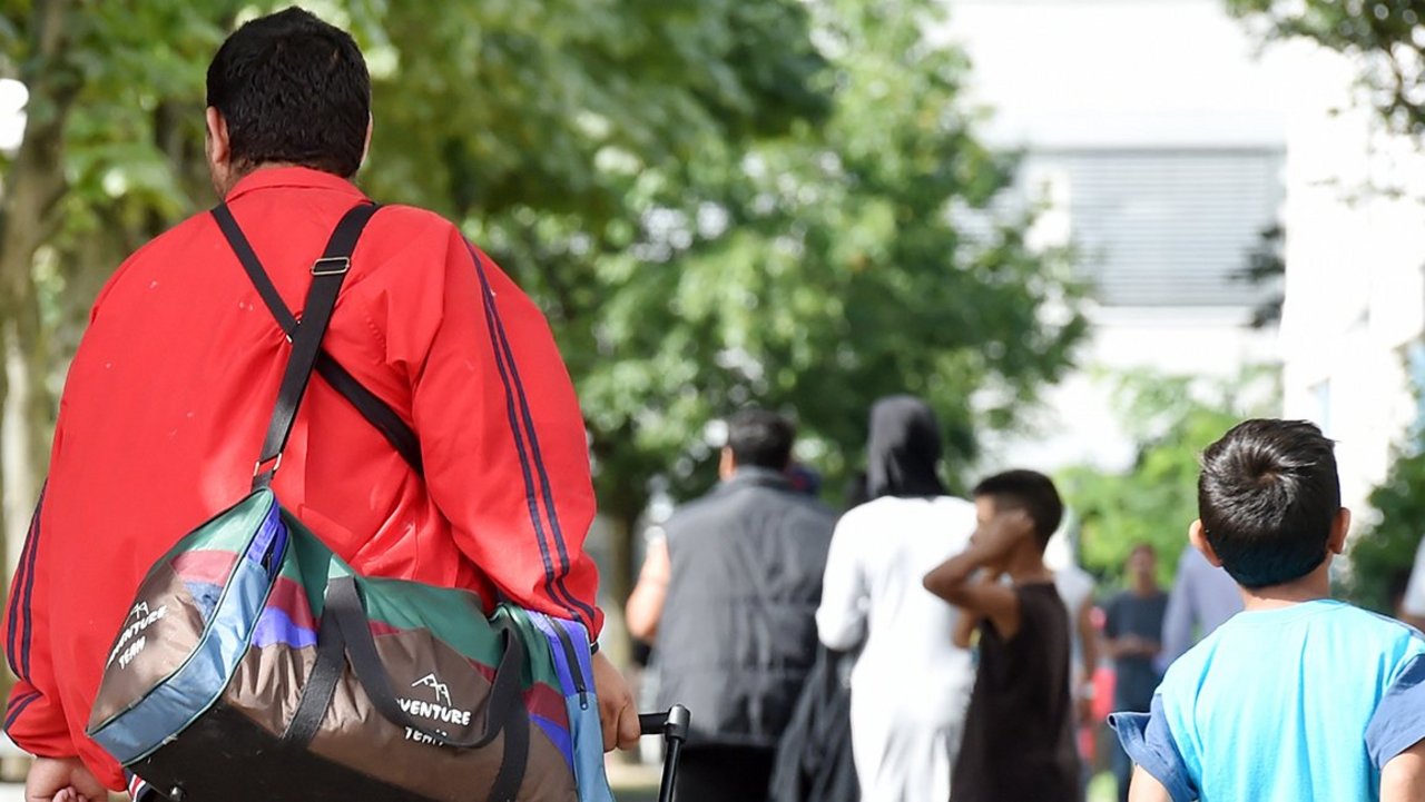 Flüchtlinge gehen am 04.08.2014 in der Landeserstaufnahme für Asylbewerber (LEA) in Karlsruhe (Baden-Württemberg) einen Weg entlang.