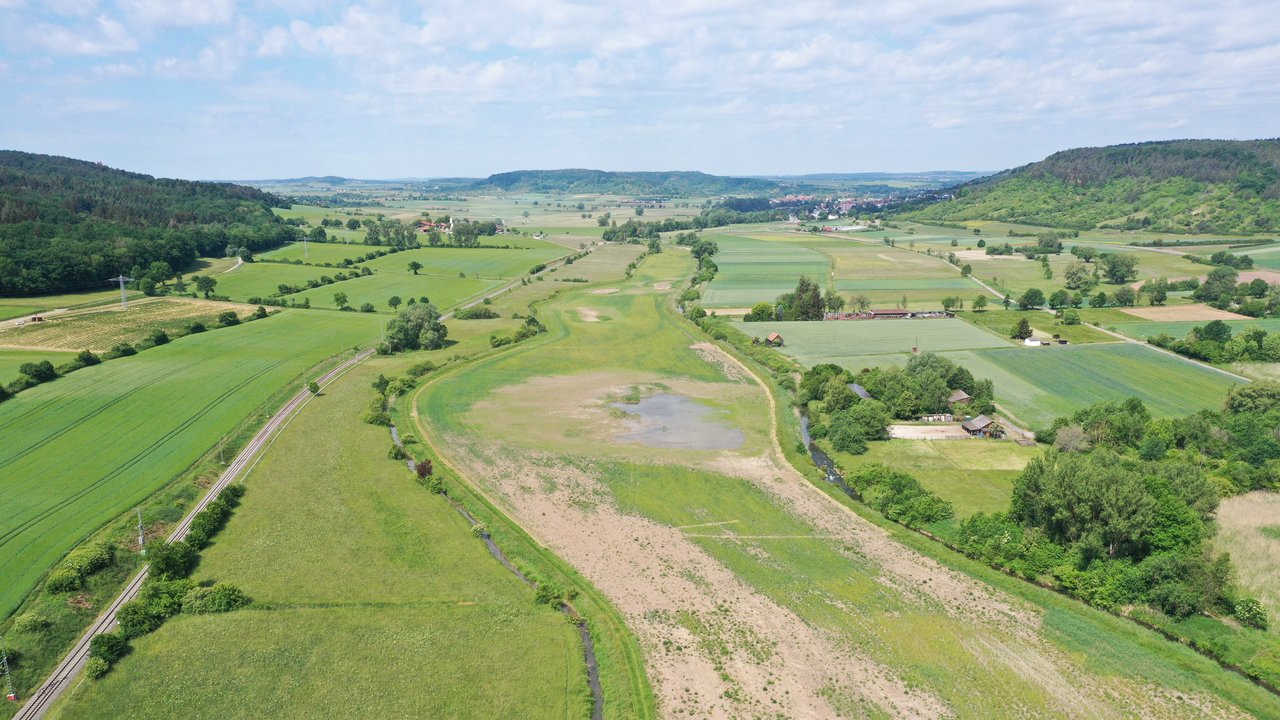 Wiedervernässte Ackerflächen im Ammertal Wiedervernässte Ackerflächen im Ammertal; Bahnlinie links; links und rechts Wald; im Hintergrund blauer bewölkter Himmel