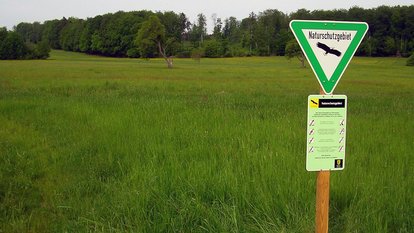 Mistwiesen Reich strukturierte Landschaft mit Wiesen, Hecken, Streuobstbäumen und Wald. Im Vordergrund steht das dreieckige Schild mit dem Naturschutzgebiete im Gelände beschildert werden.