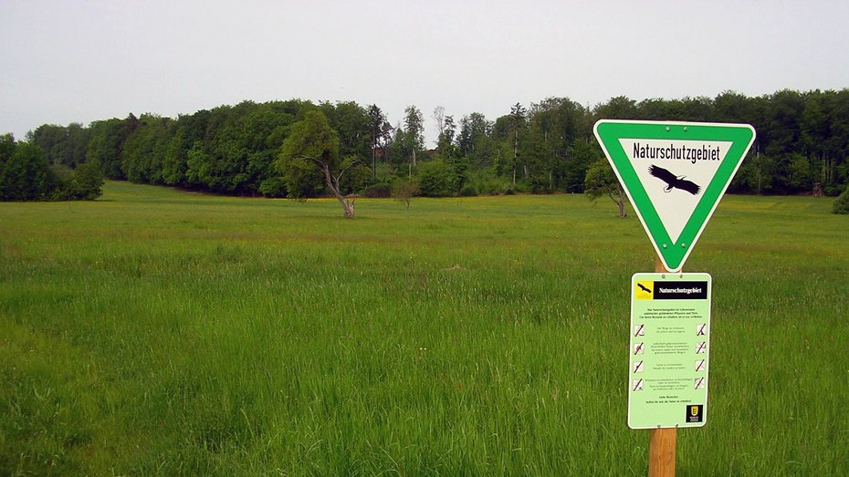 Mistwiesen Reich strukturierte Landschaft mit Wiesen, Hecken, Streuobstbäumen und Wald. Im Vordergrund steht das dreieckige Schild mit dem Naturschutzgebiete im Gelände beschildert werden.